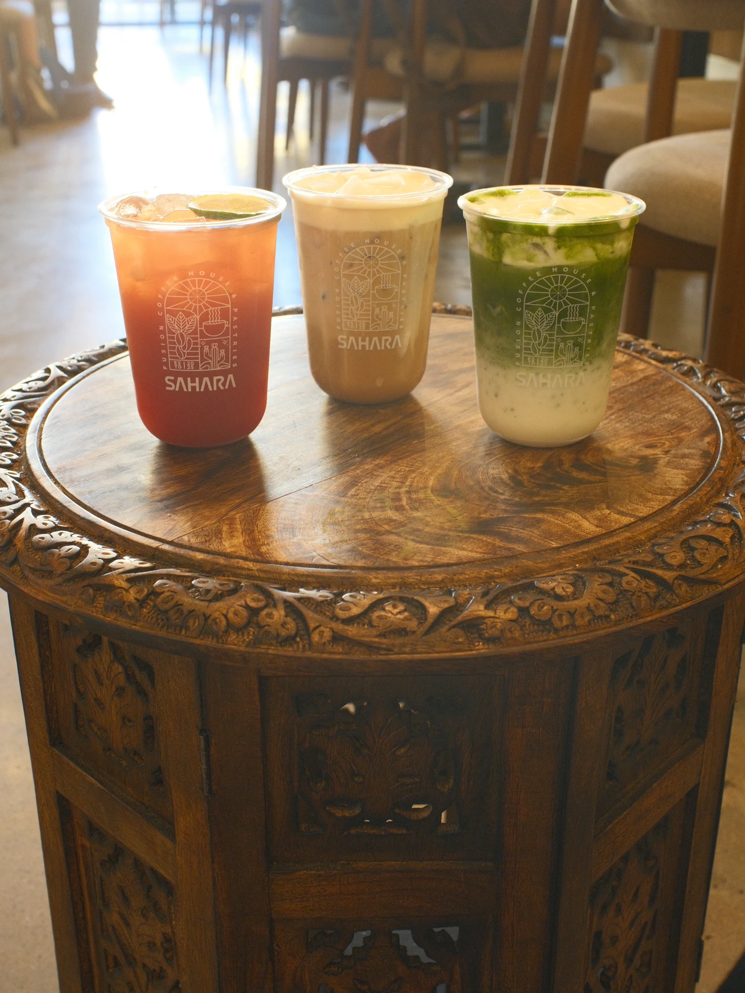 Three Sahara drinks on a carved wooden table inside the café